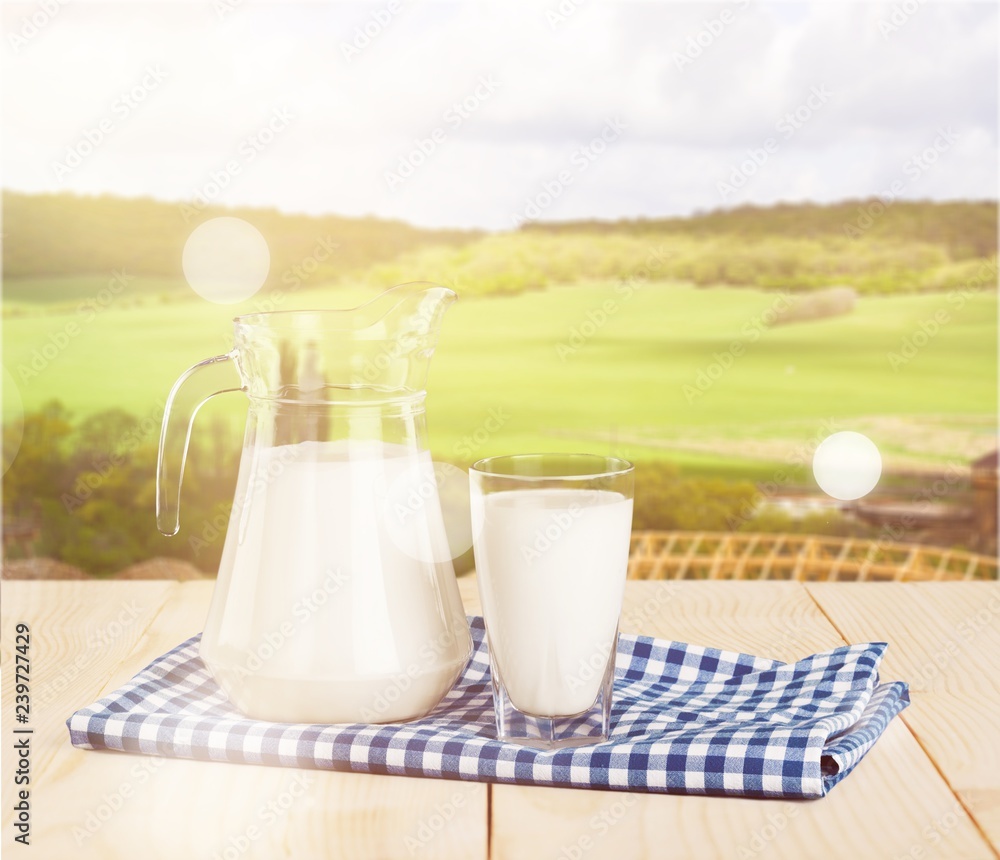 Glass of milk and jug on blurred background Glass of milk and jug on blurred background