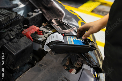 mechanic use voltmeter checking voltage of car battery in car service centre