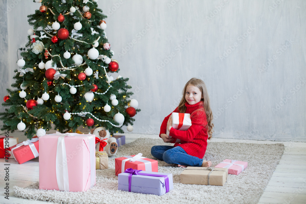 little girl opens Christmas presents new year tree decoration little girl opens Christmas presents new year tree decoration