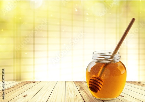 Fresh sweet honey with wooden honey dipper in glass jar isolated