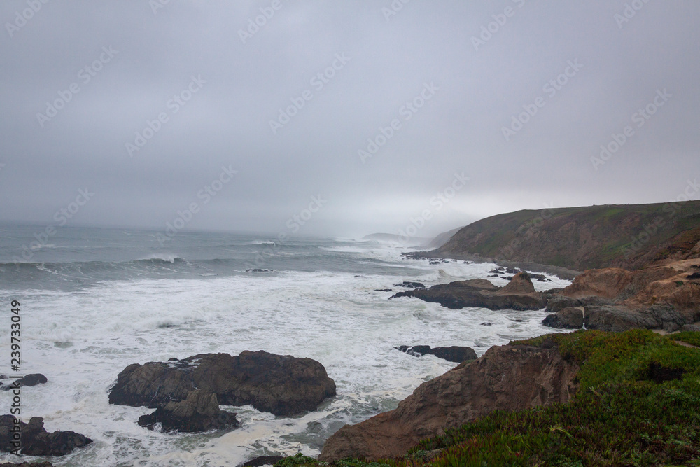 View north shows overcast skis, rocky coastline angry surf breaking over the rocky coast.