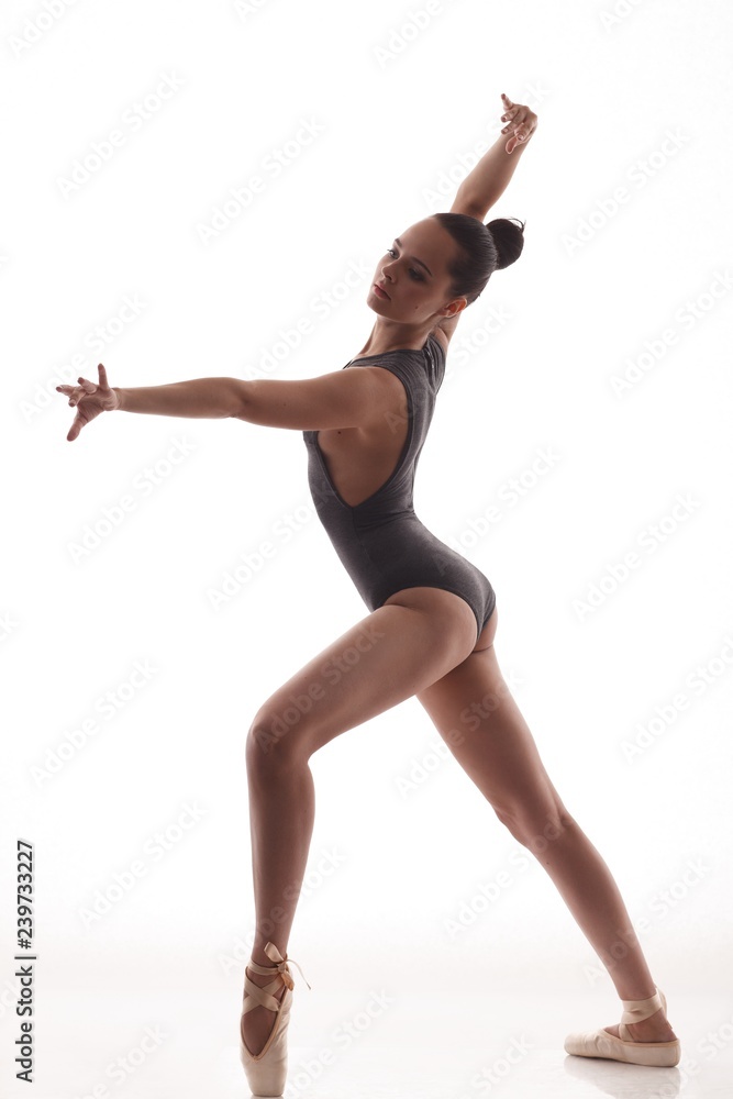Obraz premium Young beautiful ballerina is posing and dancing in a white studio