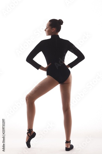 Young beautiful ballerina is posing and dancing in a white studio