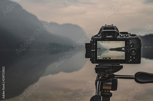 Camera on tripod at work on a misty lakeshore. Camera display. Taking pictures using the display. photo