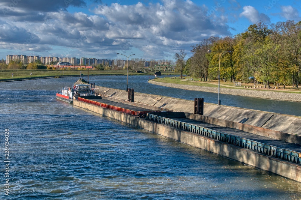 an empty barge for transporting coal flows into locks, in the background an autumn sunny landscape