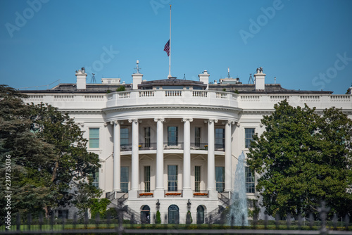 The White House, Home of the President of the United States of America in Washington, DC USA on Blue sky background. Half Staff Flag Status.