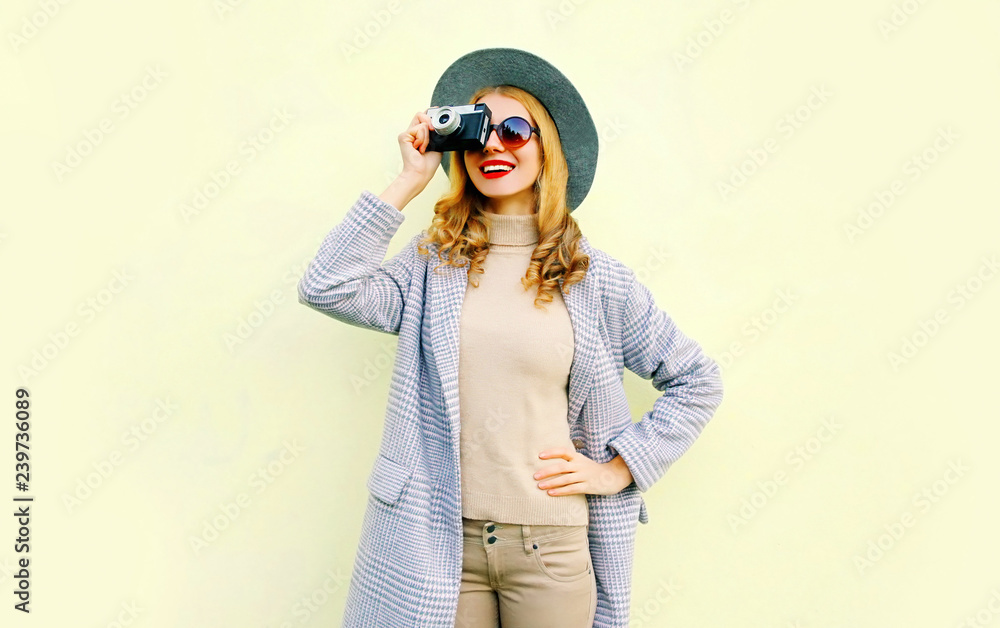 Stylish pretty smiling woman holds retro camera taking picture on background Stylish pretty smiling woman holds retro camera taking picture on background