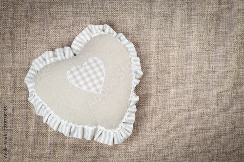 Beige heart-shaped pillow for home against the background of burlap