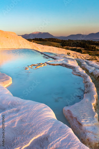Pools of Pamukkale in Turkey in sunset, contains hot springs and travertines, terraces of carbonate minerals left by the flowing water, UNESCO World Heritage Site