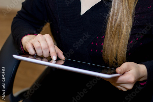 A girl holds in her hands and uses a tablet computer close up.