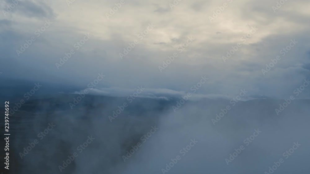 Scenic aerial view of altai mountain range with autumn forest through low clouds. Epic Aerial Flight Through Mountain Clouds. Beautiful evening Peaks Inspirational Motivational Nature Background Scenic aerial view of altai mountain range with autumn forest through low clouds. Epic Aerial Flight Through Mountain Clouds. Beautiful evening Peaks Inspirational Motivational Nature Background