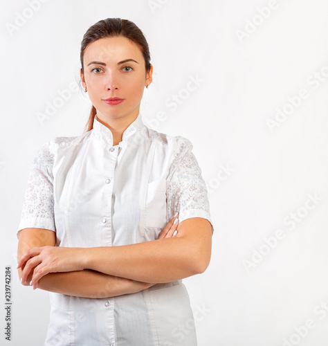 Portrait of a beautiful woman in a doctor or beautician costume on a light background