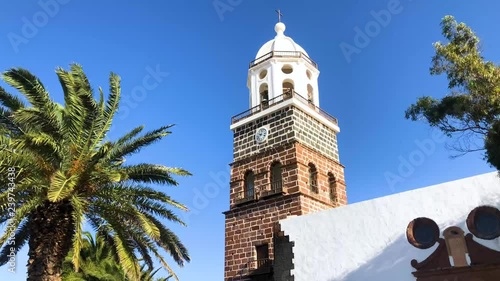 Famous clock tower and church of Nuestra Senora de Guadalupe with palms in breeze in Teguise, Lanzarote, Canary Islands, Spain, 4k footage video. photo