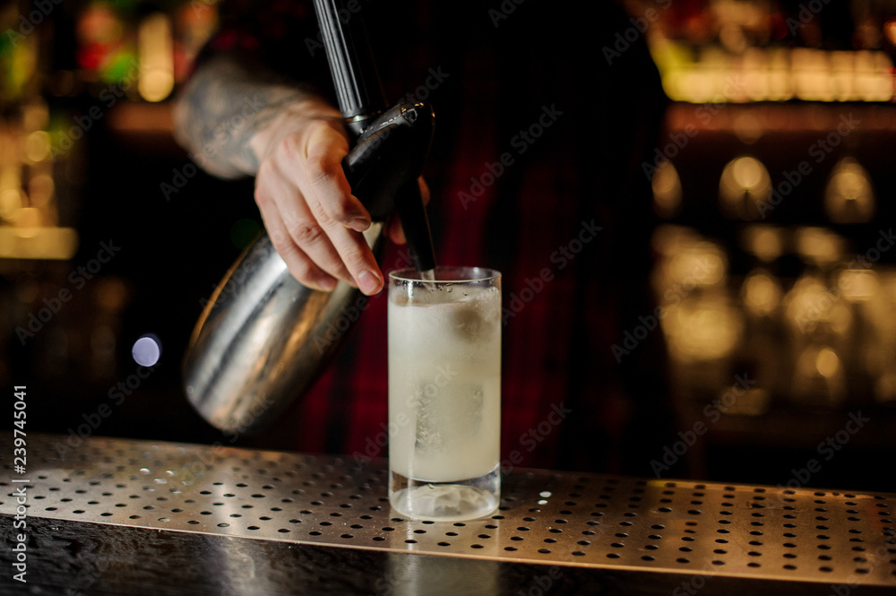Barman adding soda water to a lemonade cocktail