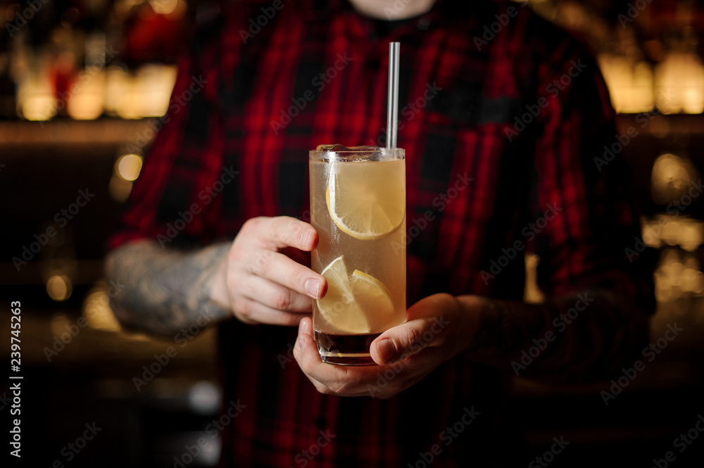 Barman holding a glass of fresh alcoholic orange cocktail