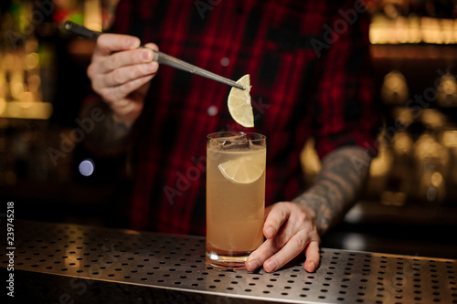 Barman decorating alcoholic lemonade with lemon slices