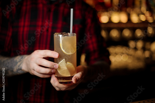 Bartender holding a glass of fresh alcoholic orange cocktail