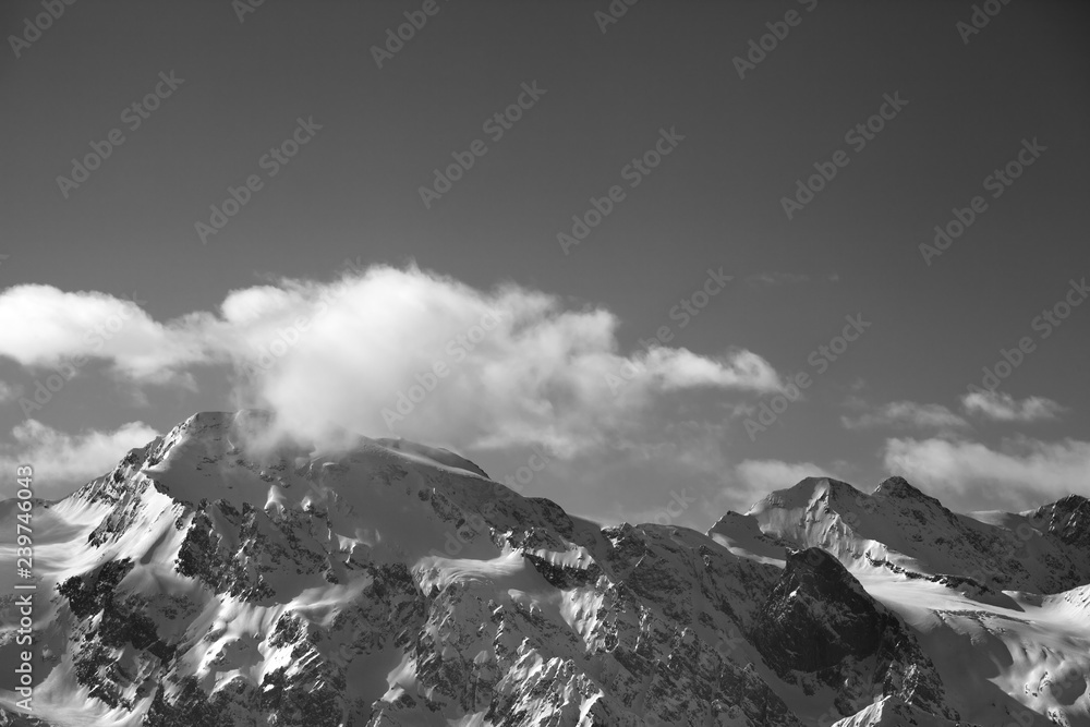 Snowy mountains with glacier and cloudy sky at sunny evening