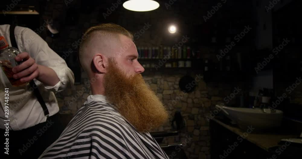 Barber applying sparkling oil to male client in Barbershop slow motion
