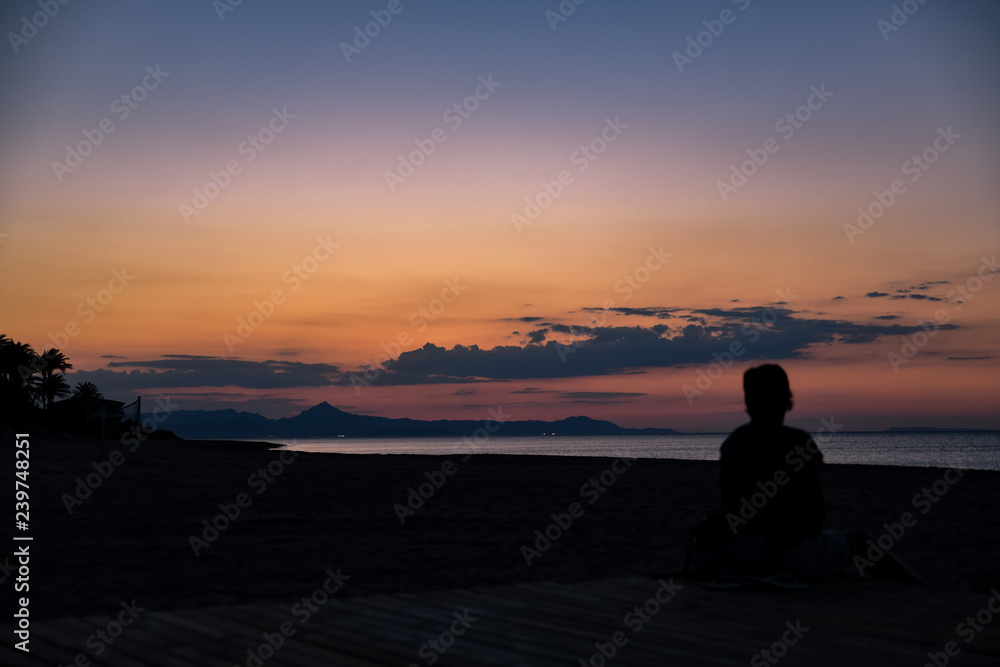 Träumerischer Sonnenuntergang mit person im gegenlicht silhouette am Meer in Denia in Spanien Valencia , dreamy sunset with silhouette on the beach in Denia Valencia in Spain