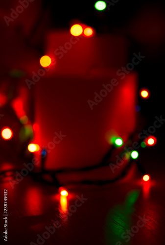 Christmas candles with glowing illumination garland. New Year winter home decoration theme. For this photo applied blurring effect.