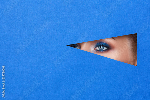 beautiful young woman in a hole in blue paper, beautiful bright make-up.
