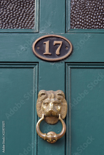 The house number 17 on a green painted door frame in Hertfordshire, with a brass lion door knocker photo