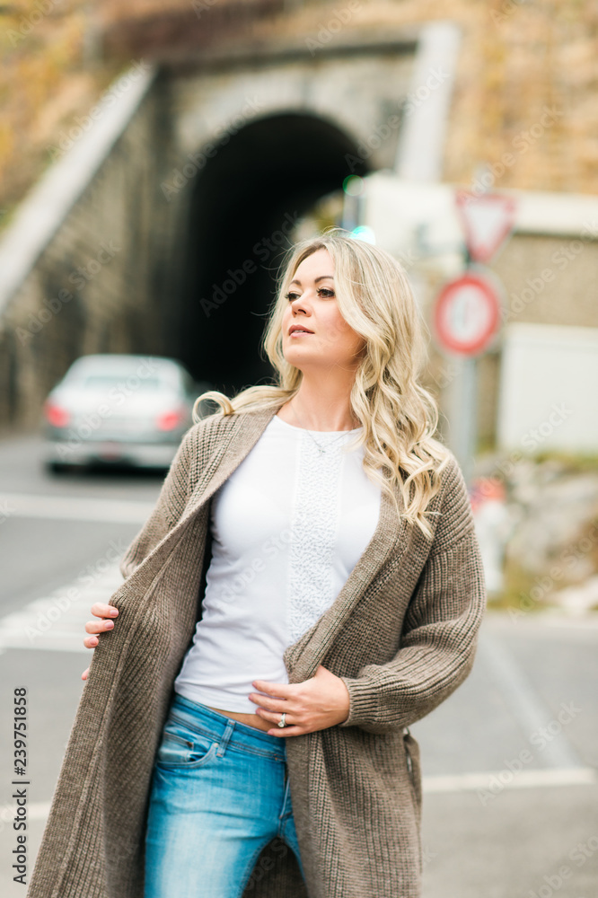 Fototapeta premium Outdoor portrait of fashion woman wearing long beige cardigan