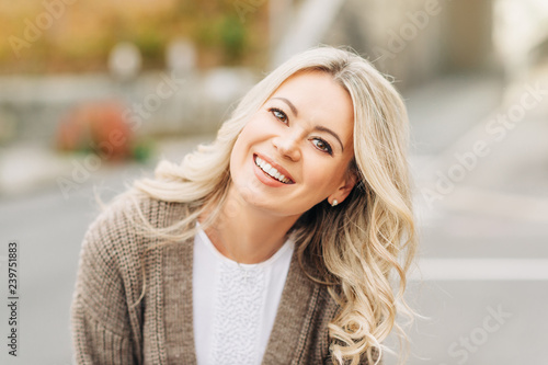 Outdoor portrait of happy smiling woman with blonde hair photo