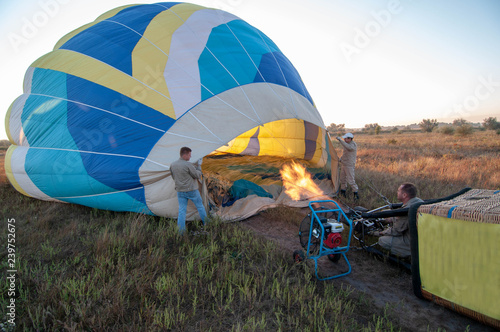 People inflate a balloon, men inflate a hot air balloon. The balloon begins to rise into the air. Flame burners for aerostat.