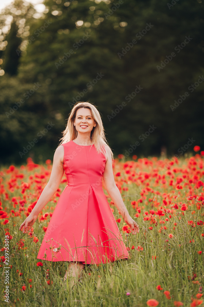 Beautiful woman enjoying nice day in poppy field, wearing pink dress Beautiful woman enjoying nice day in poppy field, wearing pink dress
