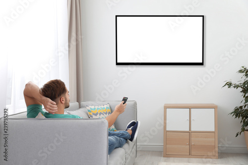 Young man watching TV on sofa at home. Mockup for design