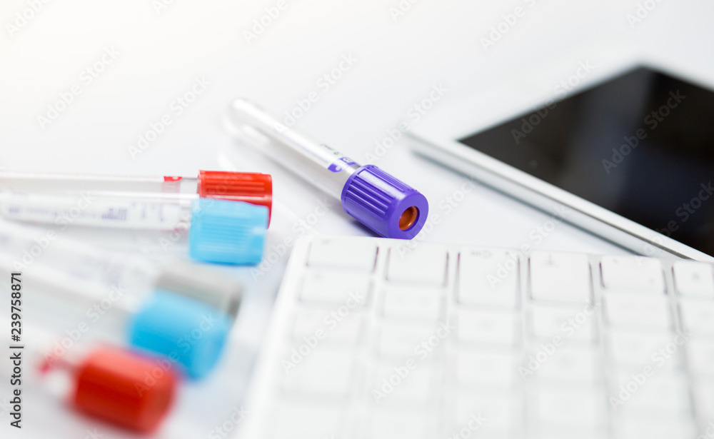 Medicine bottles for samples next to computer tablet and computer keyboard in medicine, closeup on white background Medicine bottles for samples next to computer tablet and computer keyboard in medicine, closeup on white background