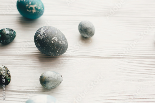 Stylish easter eggs on white wooden background with space for text. Modern easter eggs painted with natural dye in grey marble color. Happy Easter  greeting card