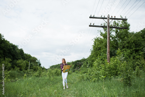 Portrait of a beautiful blond girl in tartan shirt walking with a map in the countryside.