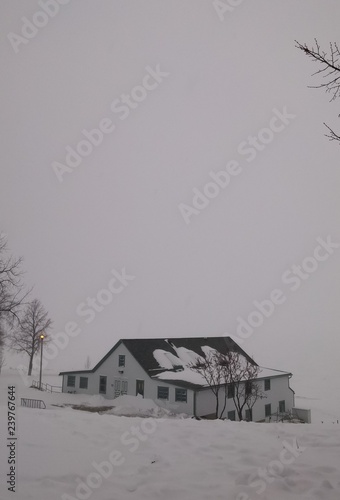 Small white cabin covered in snow in a winter weather with extreme cold.