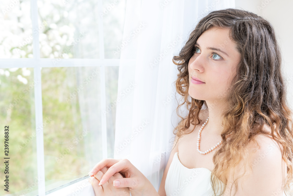 Closeup side, profile portrait of young female person, woman, bride in wedding dress with pearl necklace, hair, face standing, looking through glass window, white curtains at view, thinking Closeup side, profile portrait of young female person, woman, bride in wedding dress with pearl necklace, hair, face standing, looking through glass window, white curtains at view, thinking