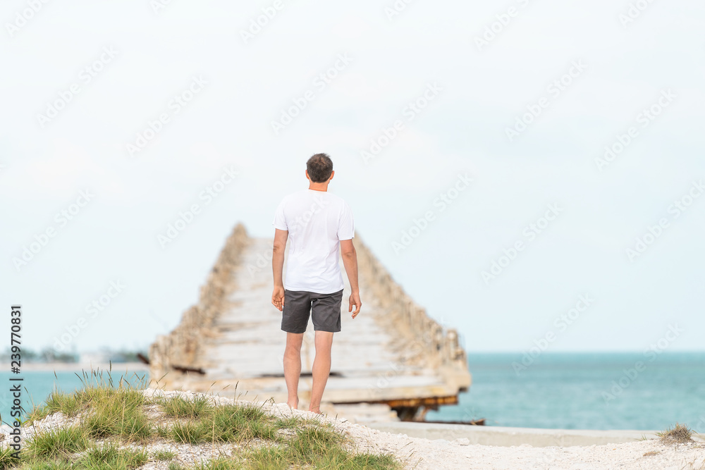 Young man standing in front of Old Seven Mile Bridge, Knights Key-Pigeon Key-Moser Channel-Pacet Channel, tourist on vacation, horizon seascape in Bahia Honda key in Florida, looking at sea, ocean