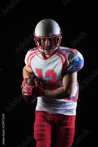 American football player wearing helmet ready to throw ball on black background