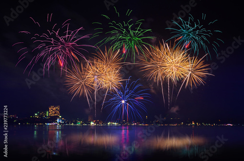 Colorful fireworks celebration and the city night light with twilight sky background.
