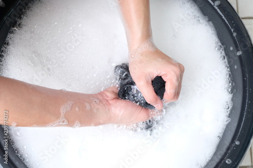 A woman washes clothes by hand in the soapy water, isolated on white background.