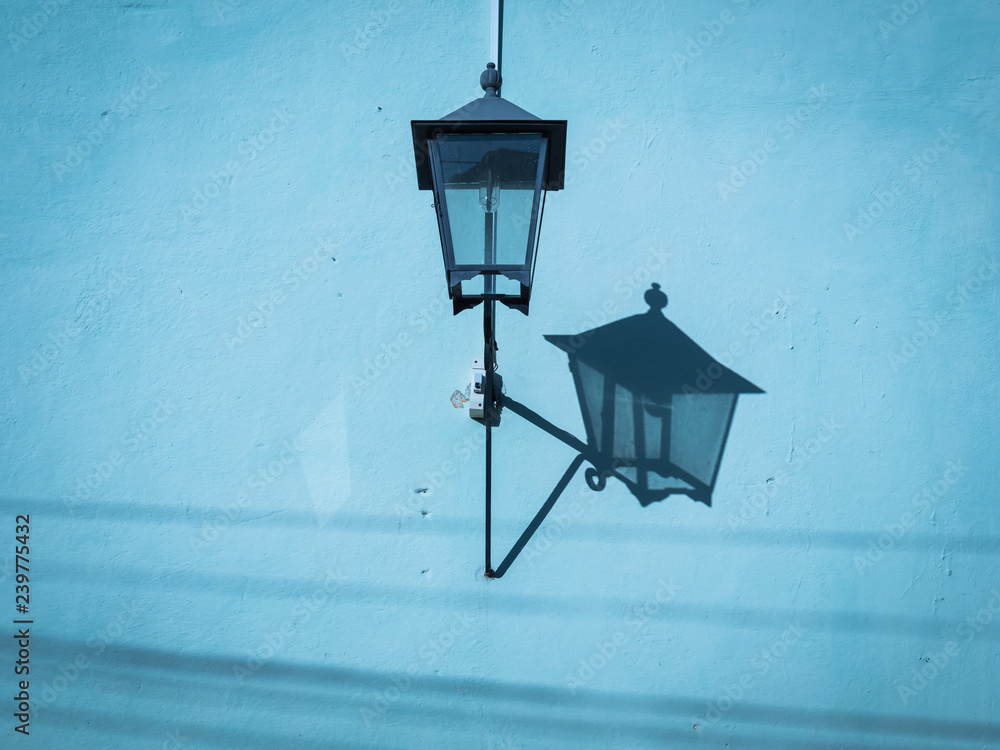 Colonial street lamp casting shadow on a blue wall in Trinidad Cuba