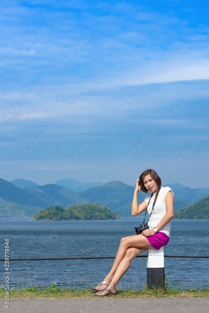 Women and the camera sitting on a concrete pillar at Kaeng Krachan dam phetchaburi , Thailand. Women and the camera sitting on a concrete pillar at Kaeng Krachan dam phetchaburi , Thailand.