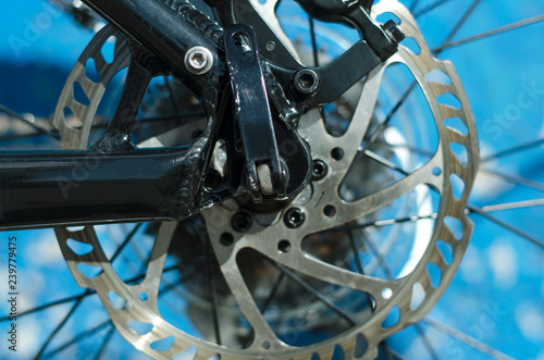 Disk brake of mountain bike close up on a blue wall background.