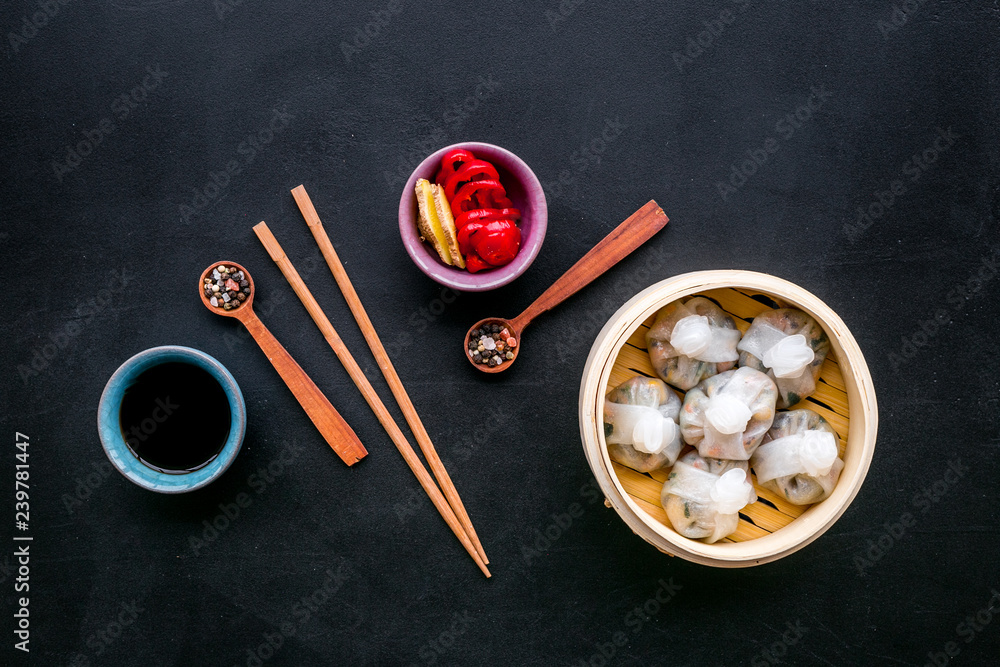 Dinner in Chinese restaurant with dim sum, sticks and tea on black background top view Dinner in Chinese restaurant with dim sum, sticks and tea on black background top view