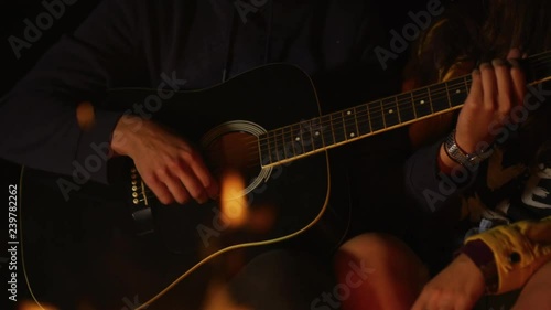 Sitting by a campfire and playing guitar