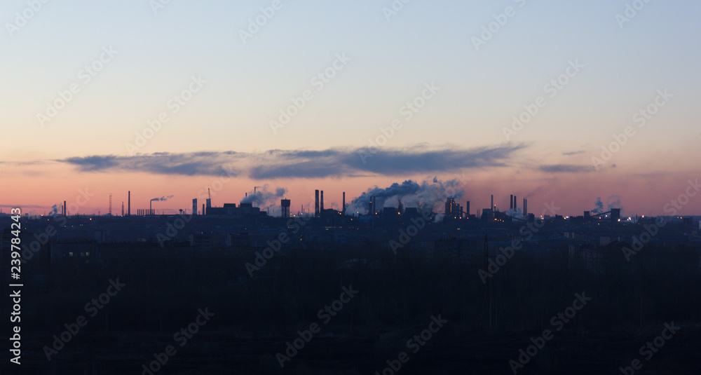 Panorama of the city in the morning dawn with a steel mill on the horizon and smog from toxic emissions in the cloudless sky