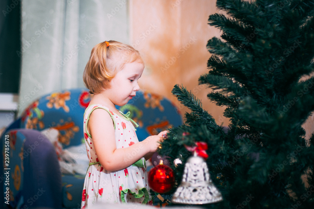 little baby decorates the Christmas tree