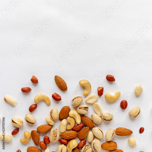Assorted roasted and raw nuts scattered on white