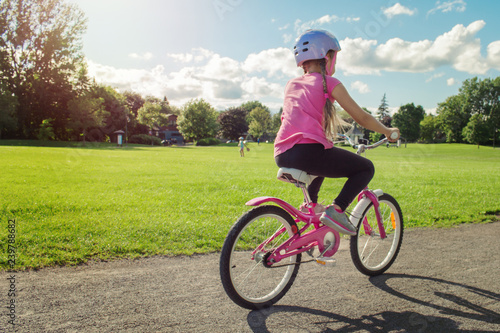 Girl in a helmet riding a bicycle. Cyclist in summer park.